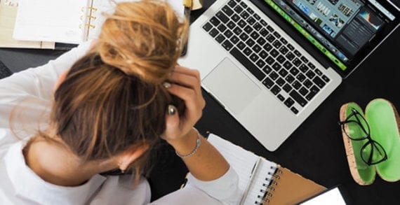 Stressed woman holding her head, staring down at her desk Fear, panic and leadership in business