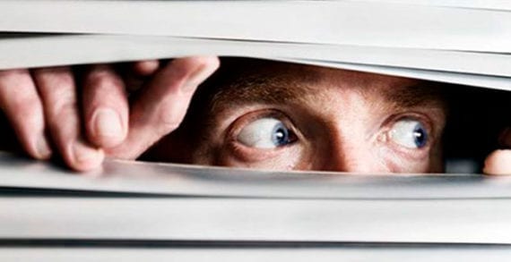 Scared man looking through slats of a blind Do you suffer from a false sense of no confidence?